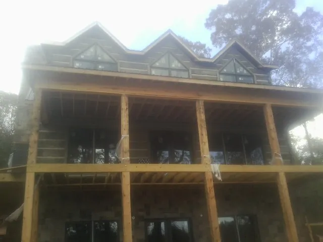 Dormers and porch framing on a large log home under construction — Roof Coating work by our crew in Wrightwood
