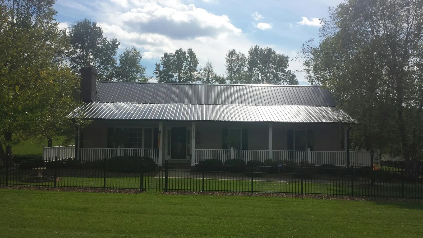 Gray metal roof on a brick ranch with a full width front porch — Gutter Guard Installation work by our crew in Wrightwood