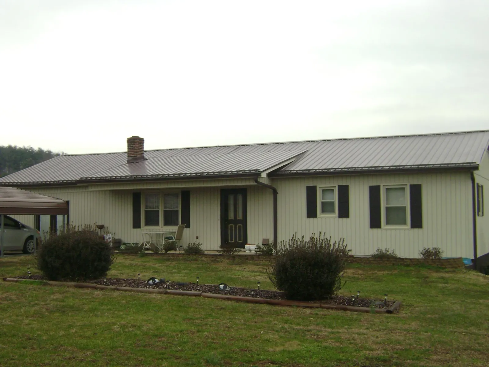 Brown metal roof on a cream sided ranch home with a brick chimney in Wrightwood