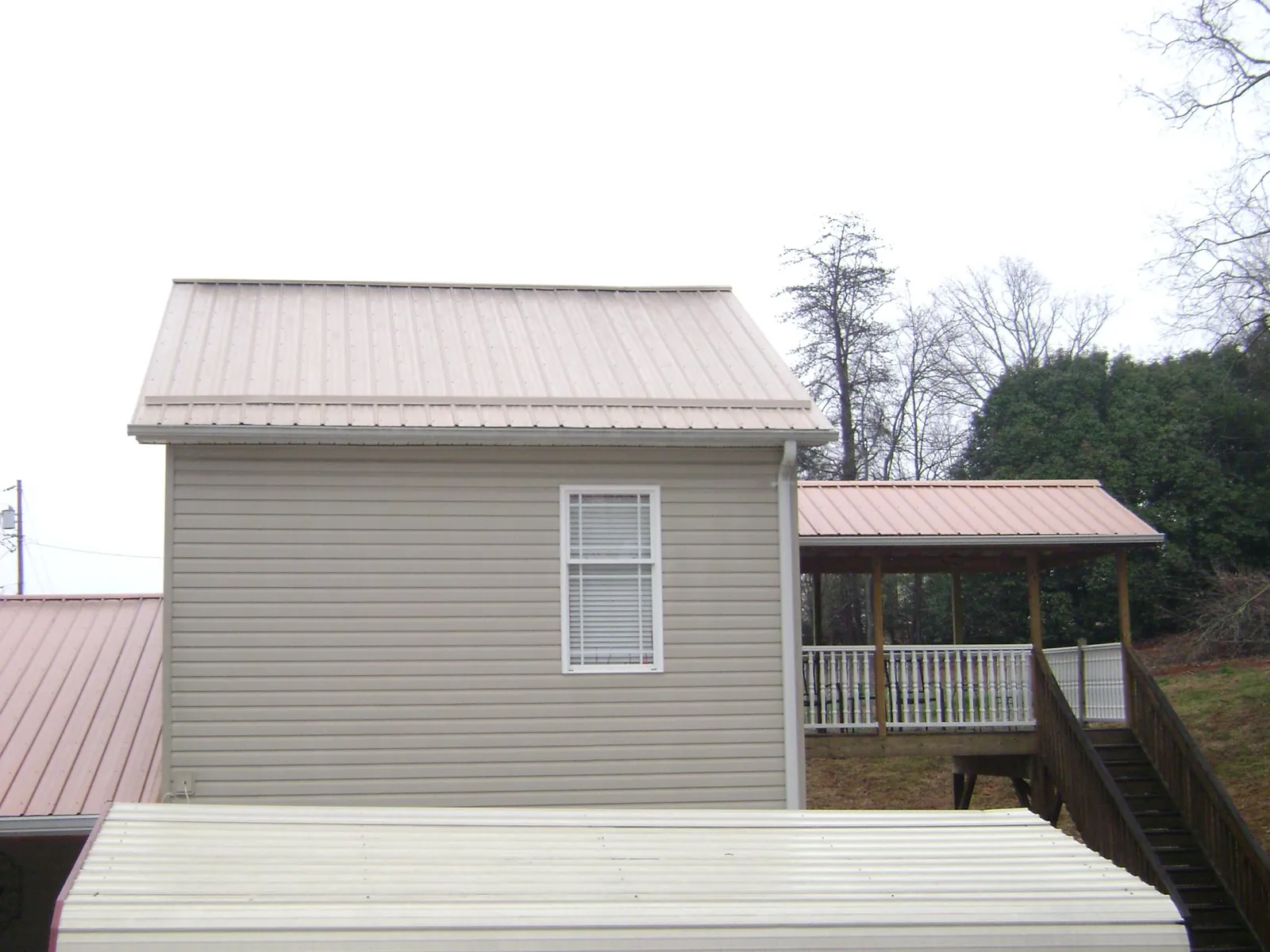 Tan metal roofs on a two story addition and attached porch, from a Roof Replacement job in Wrightwood