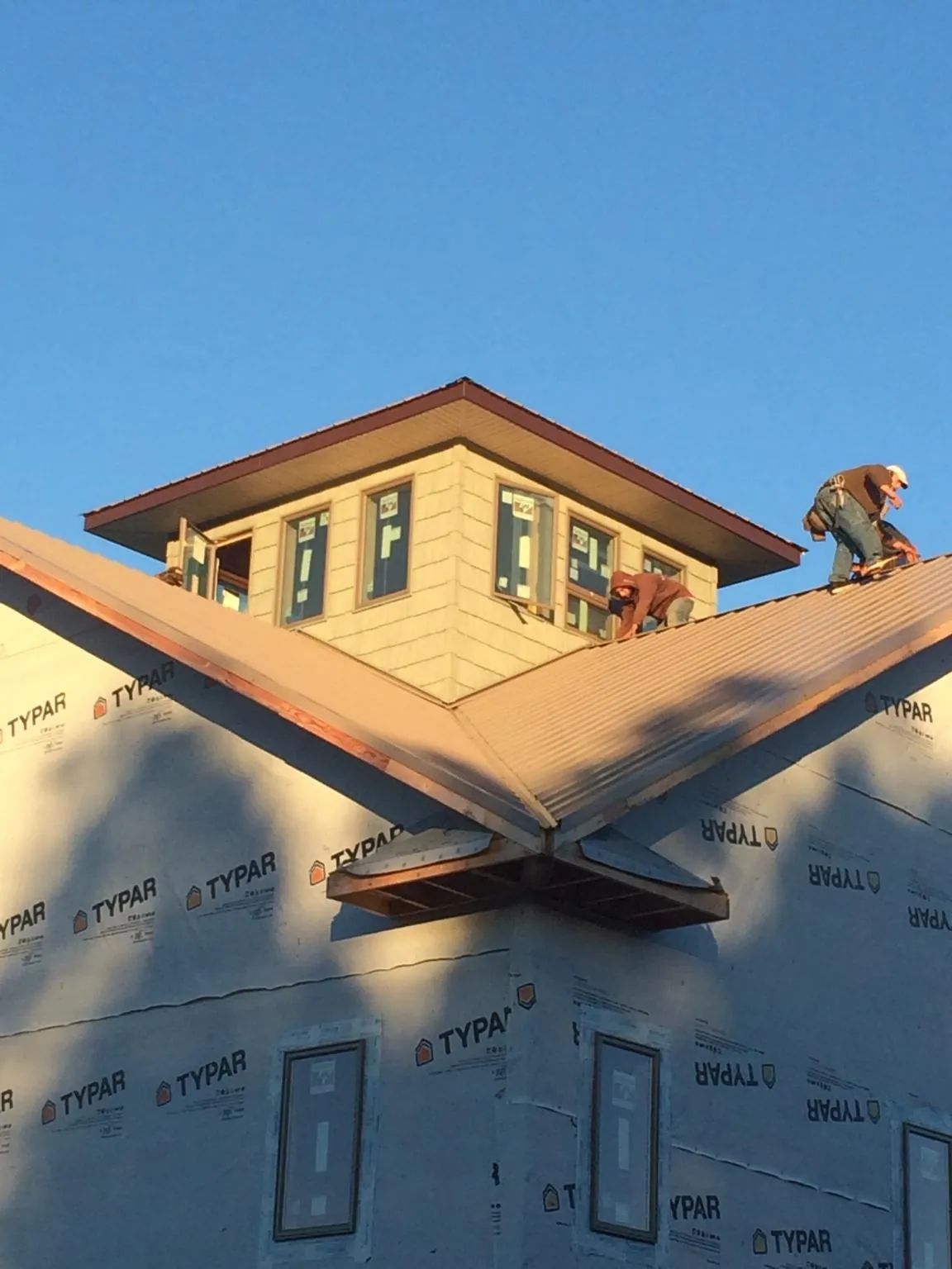 Roofers working around a rooftop cupola on a new metal roof at sunset — Roof Waterproofing in Wrightwood by Roofing Brothers